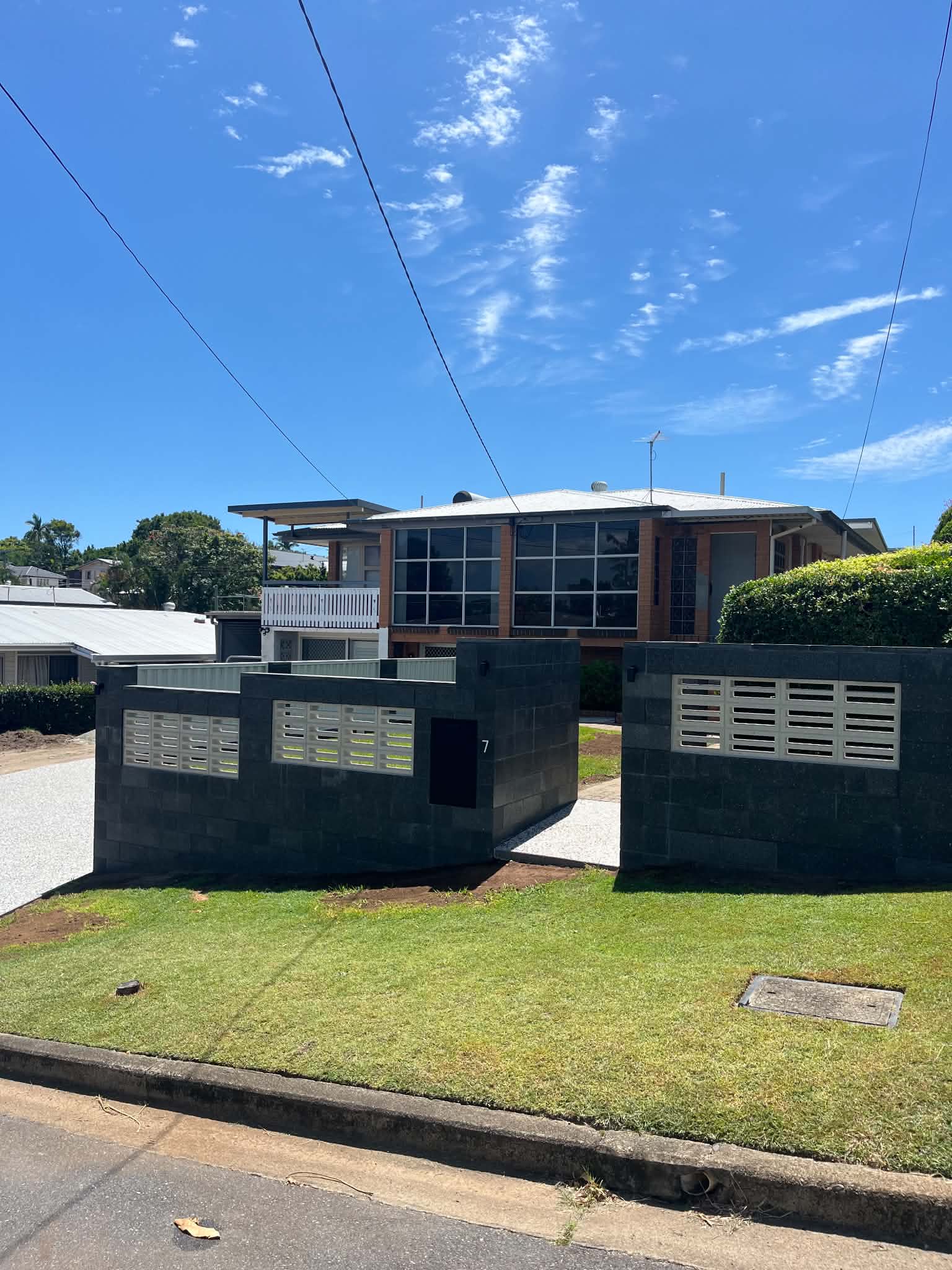 Charcoal block front fence with pale feature panels beside a home