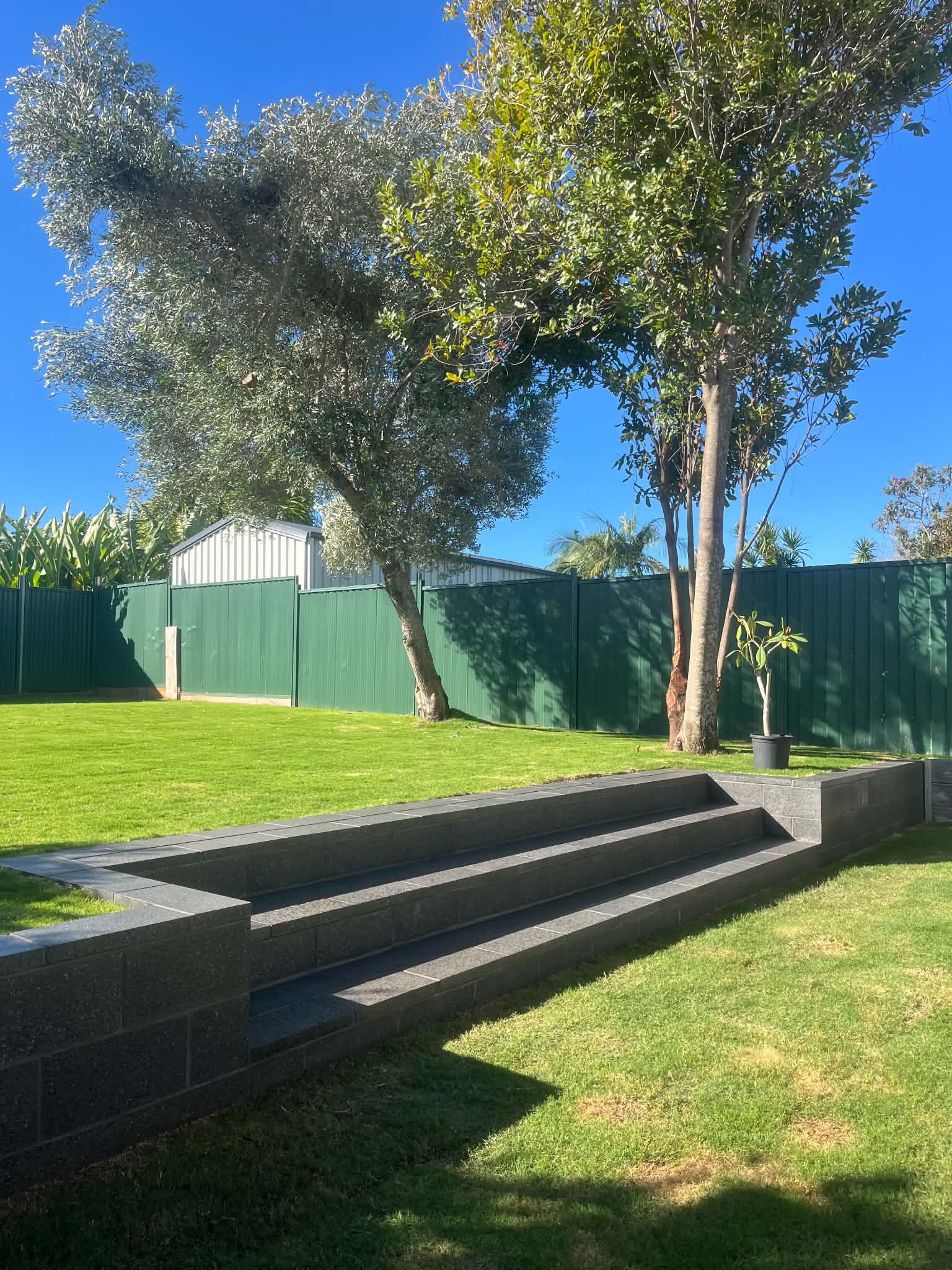 Completed charcoal block steps and retaining walls beside a lawn