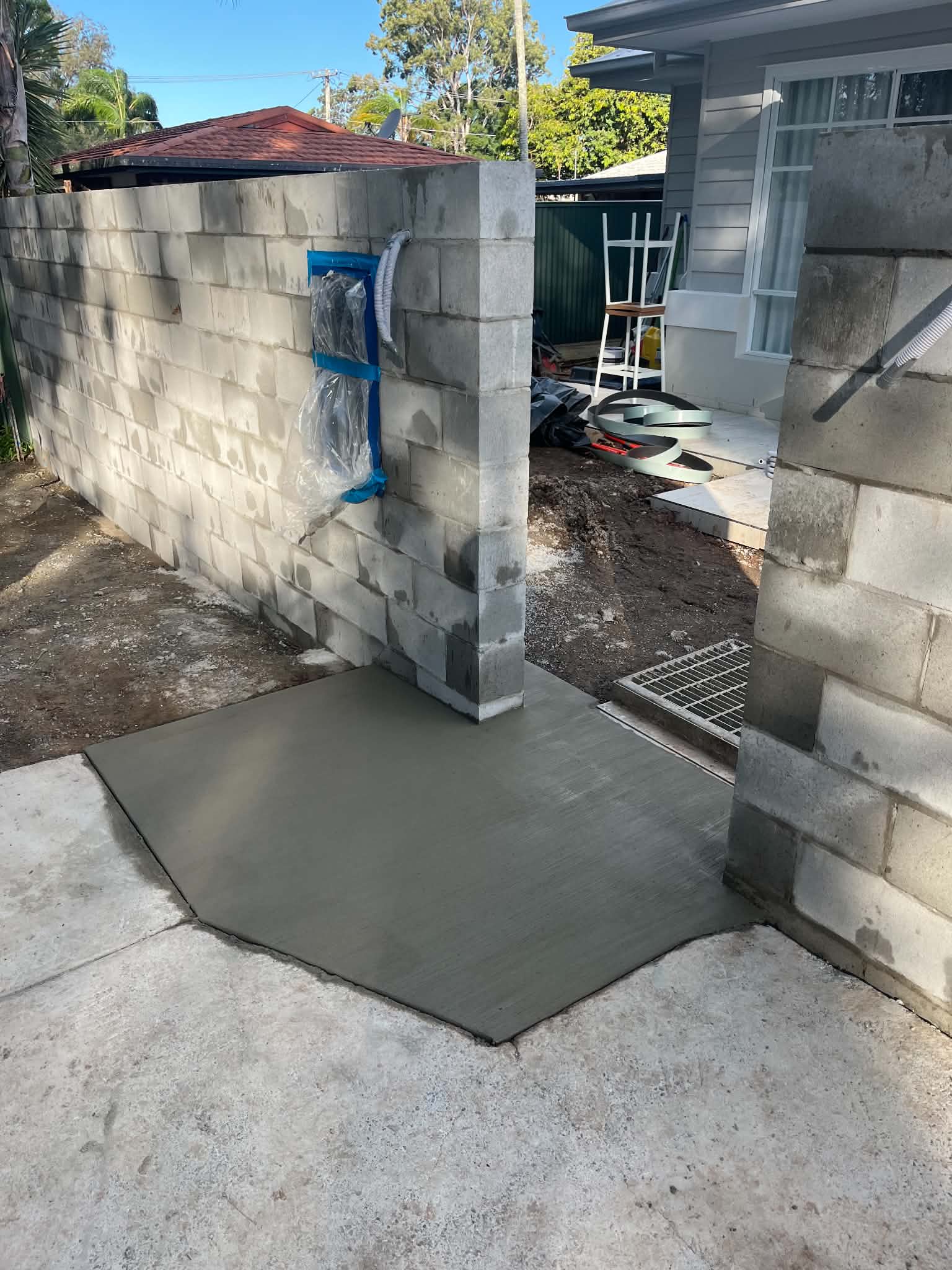 Unfinished front fence opening with block piers and a fresh concrete path