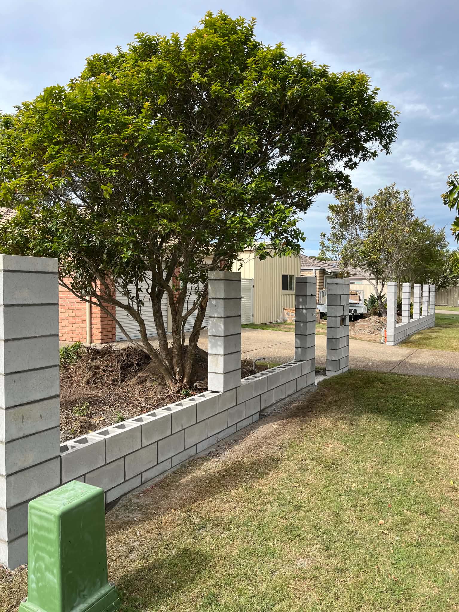 Low unfinished block fence and piers across a residential front yard