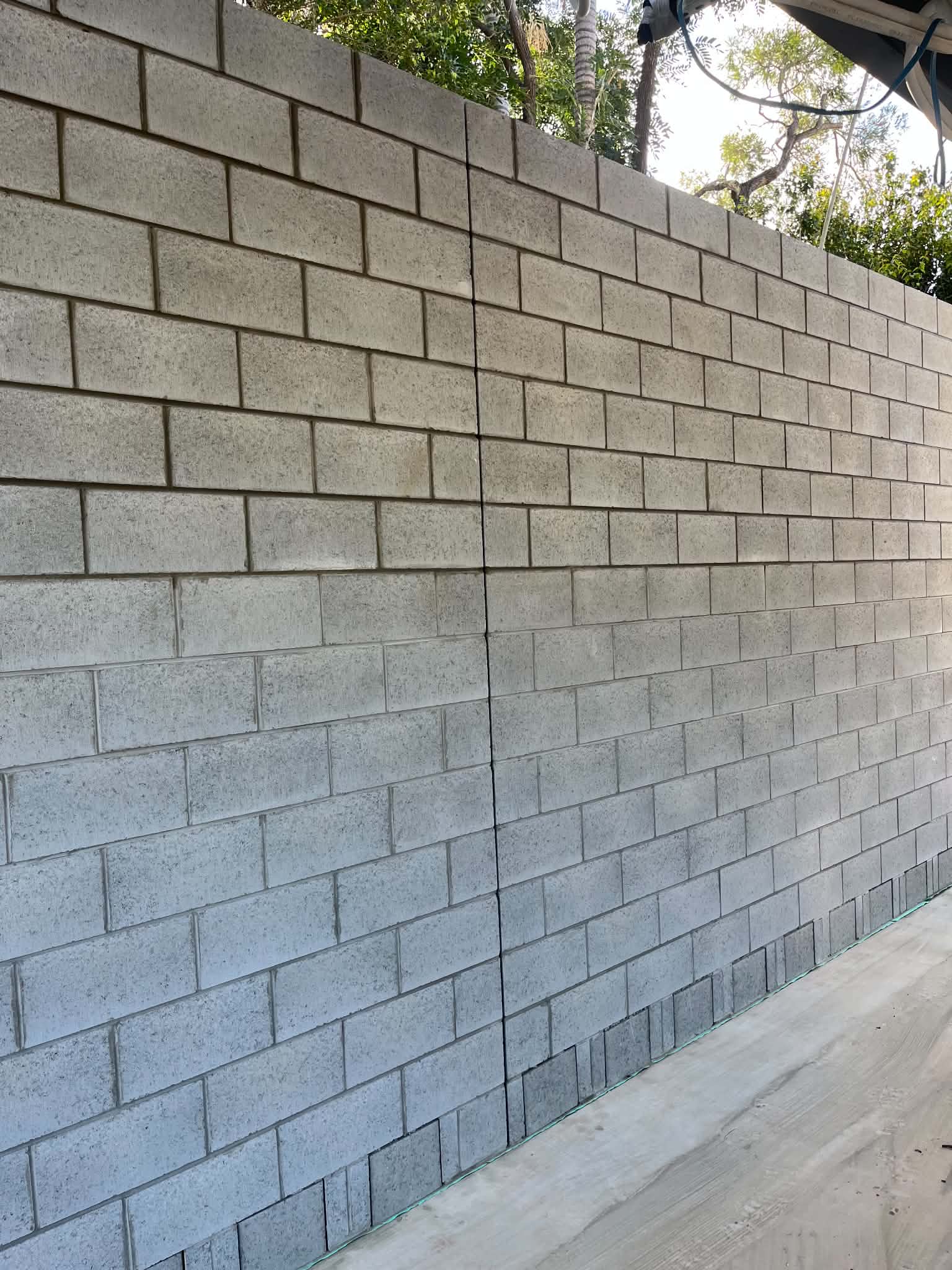 Close view of long grey block wall beside a concrete path