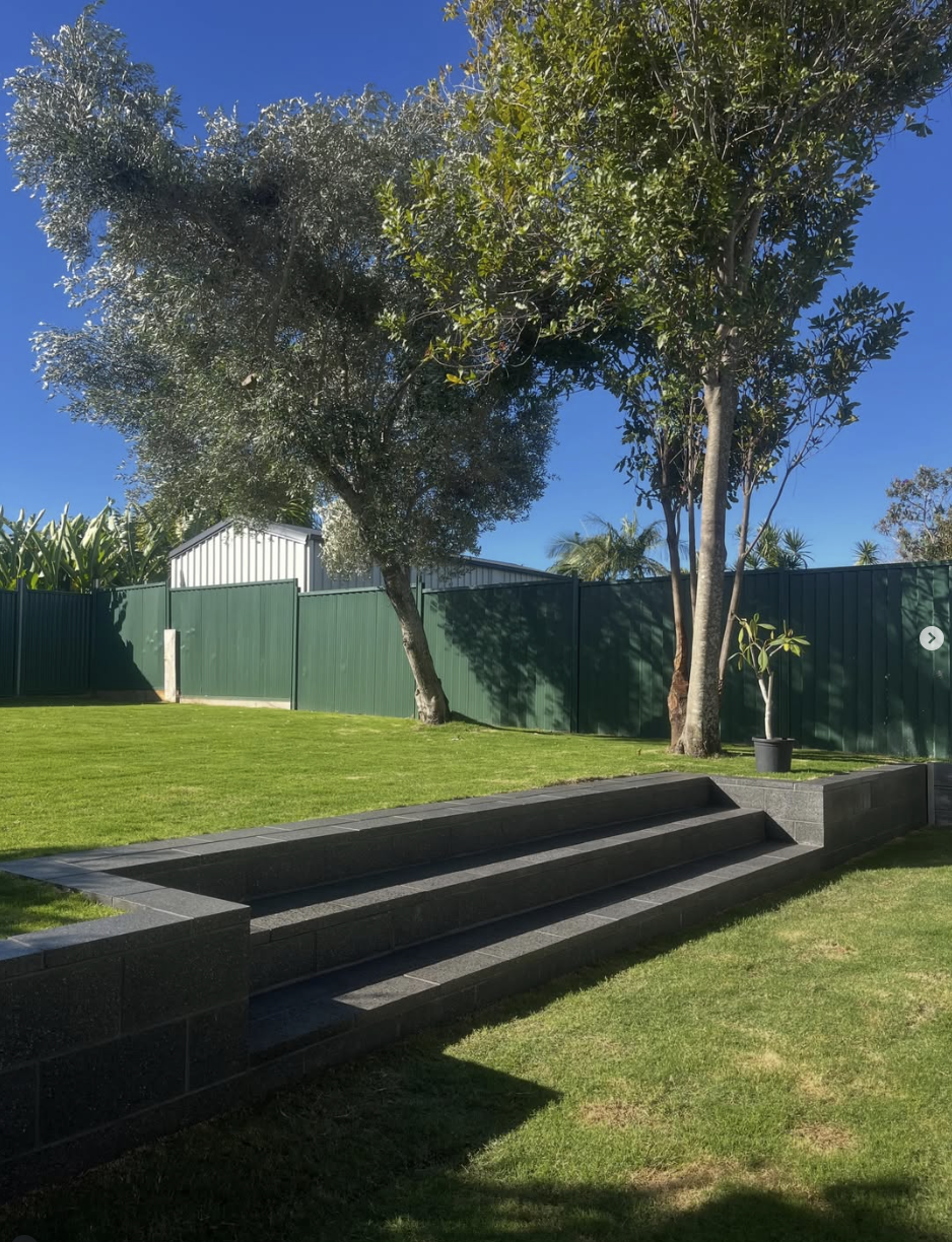 Completed charcoal block steps and retaining walls beside a lawn
