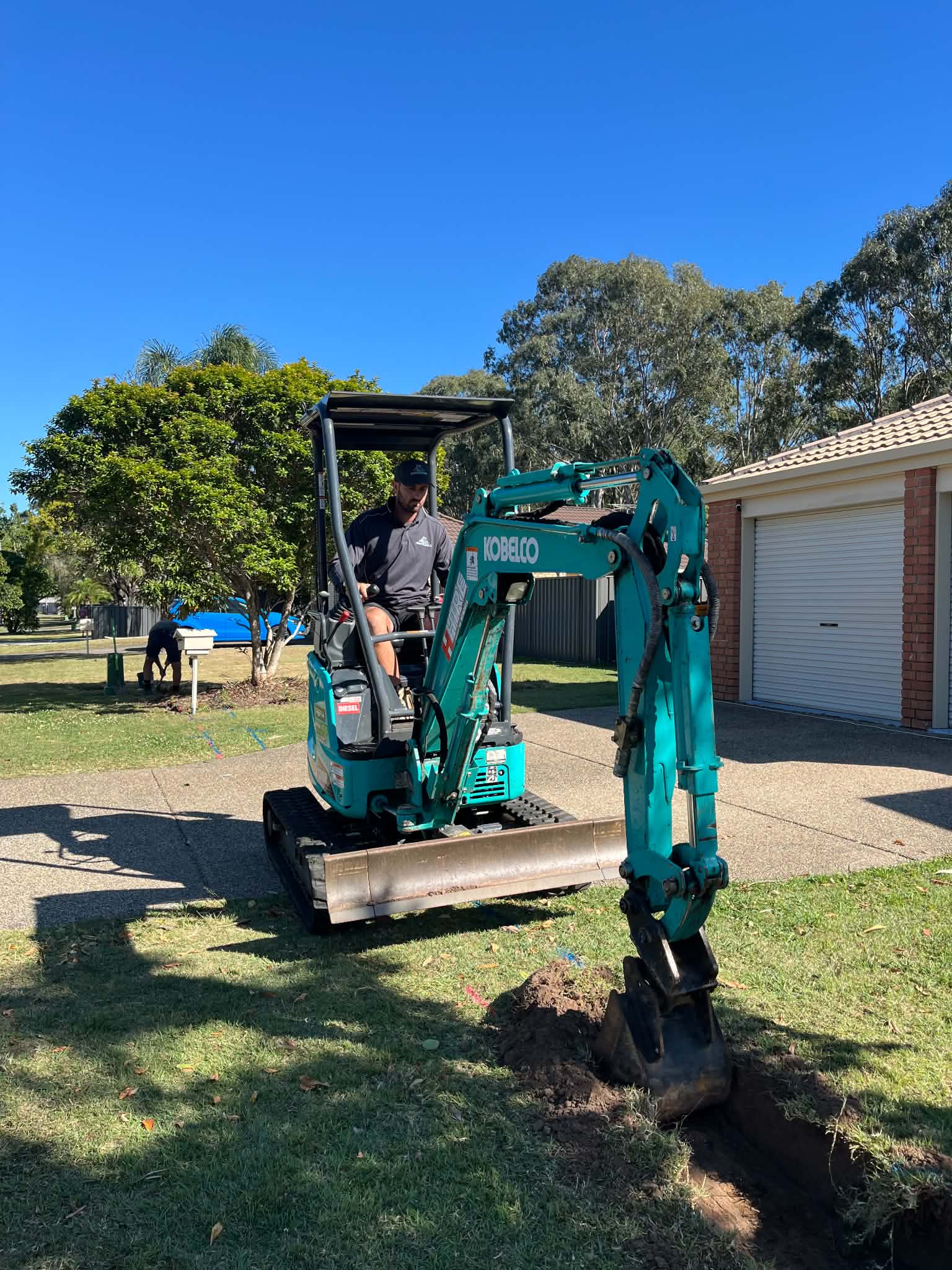 Mini excavator working on a residential front lawn